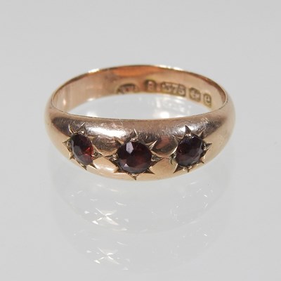 Lot 26 - A 9 carat gold three stone garnet ring