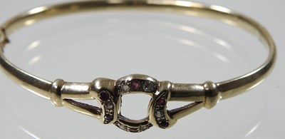 Lot 19 - A 9 carat gold hinged bangle, set with rubies...