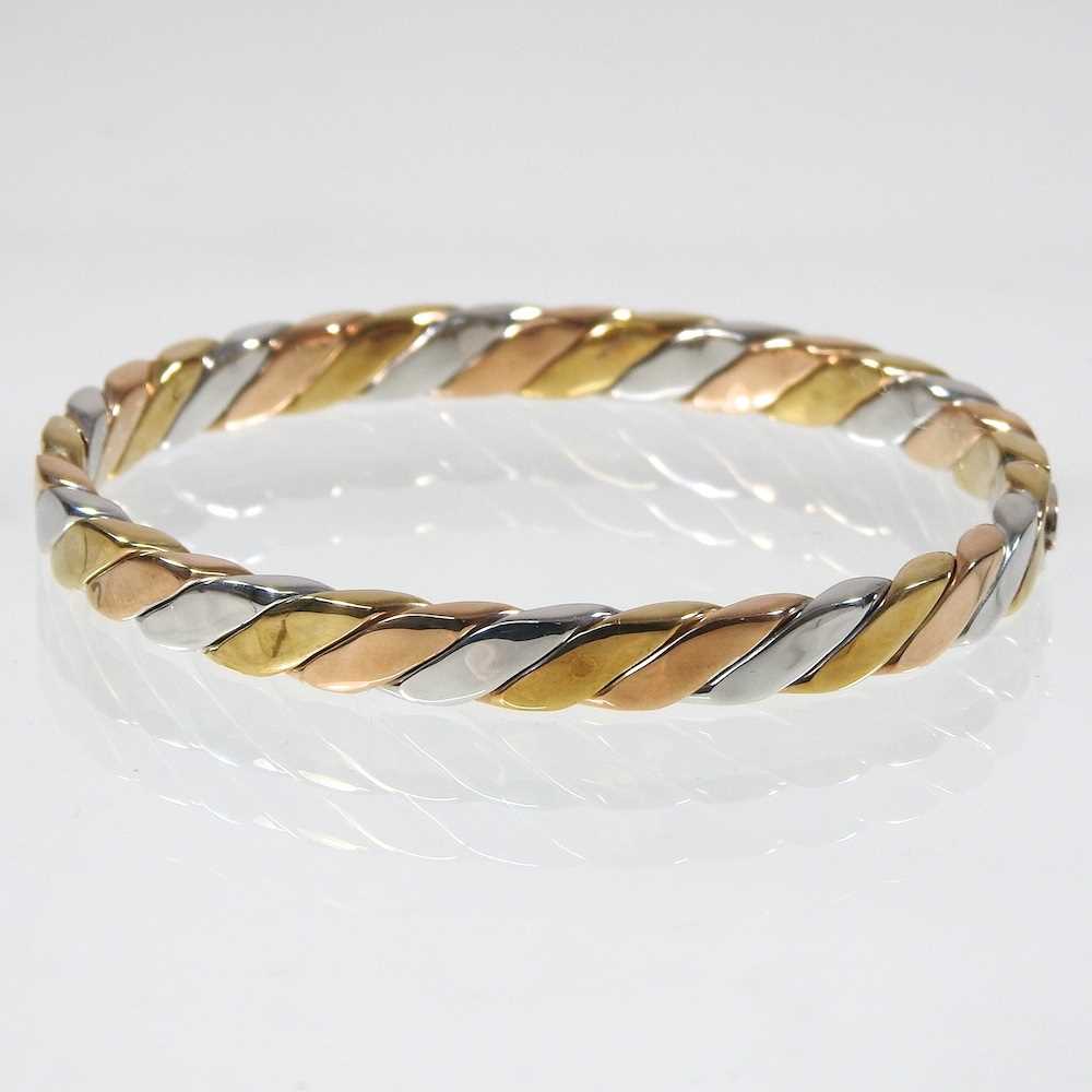 Lot 35 - A 9 carat three colour gold bangle, of hinged...