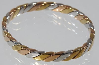 Lot 35 - A 9 carat three colour gold bangle, of hinged...