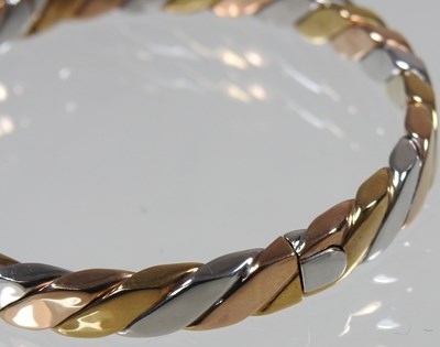 Lot 35 - A 9 carat three colour gold bangle, of hinged...