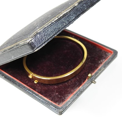 Lot 1 - An Edwardian 14 carat gold bangle, of hinged...