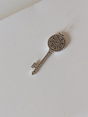 Lot 119 - An 18ct white gold Tiffany diamond key pendant,...