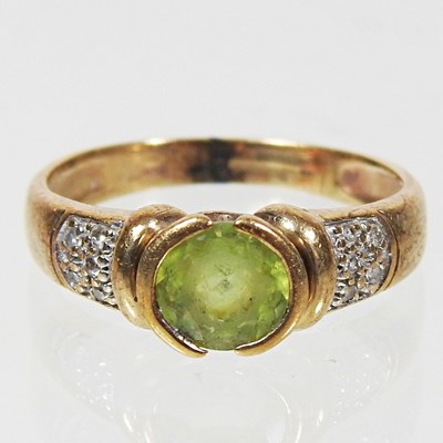 Lot 180 - A 9 carat gold, peridot and diamond dress ring,...