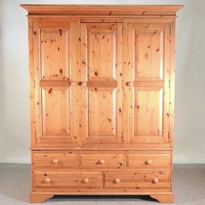 Lot 670 - A modern pine triple wardrobe, with drawers below