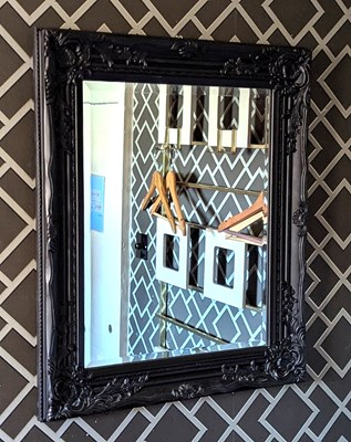 Lot 159 - An ornate black painted wall mirror, having a...