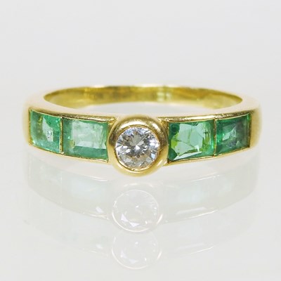 Lot 27 - An 18 carat gold diamond and emerald ring, the...