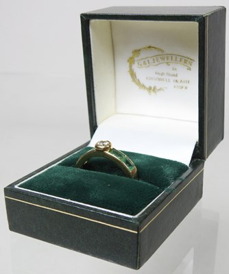 Lot 27 - An 18 carat gold diamond and emerald ring, the...