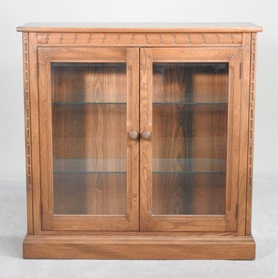 Lot 387 - A 1970s Ercol elm glazed dwarf bookcase, on a...