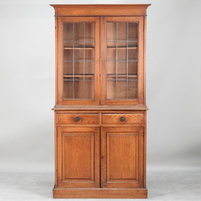 Lot 673 - An Edwardian oak lead glazed cabinet bookcase,...
