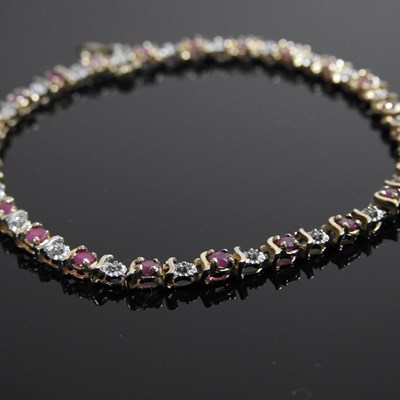 Lot 461 - A 9 carat gold diamond and ruby line bracelet,...