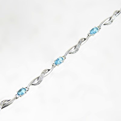 Lot 620 - A 9 carat white gold and blue topaz flexible...