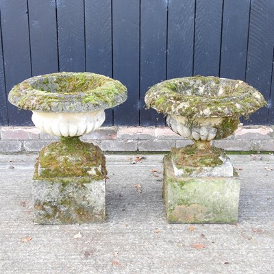 Lot 122 - A pair of cast stone garden urns, each on a...