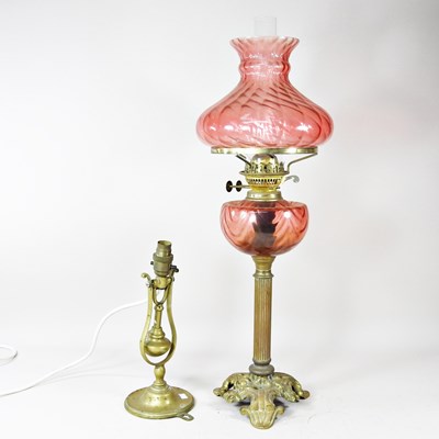Lot 225 - A brass oil lamp with a cranberry glass shade,...