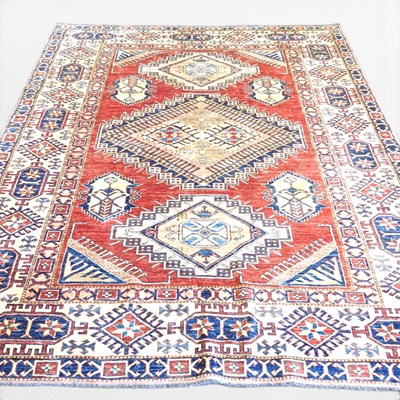 Lot 592 - A large Kazak rug, with three central hooked...