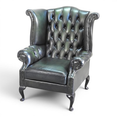 Lot 77 - A green leather upholstered wing armchair,...
