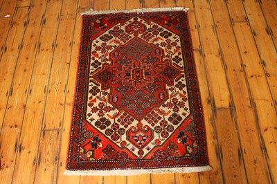 Lot 533 - A Persian red wool rug with a floral central...