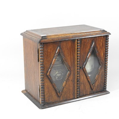 Lot 694 - A 1920s oak smokers' cabinet, with a fitted...