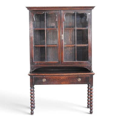 Lot 367 - A 1920s oak glazed cabinet on stand, on bobbin...