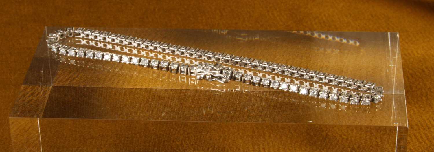 Lot 13 - A 9 carat white gold and diamond line bracelet,...