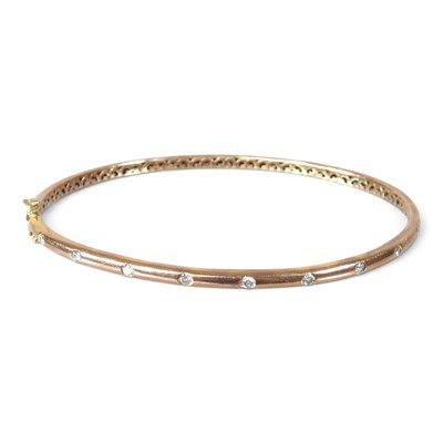 Lot 64 - A 9 carat gold and diamond bangle, of hinged...